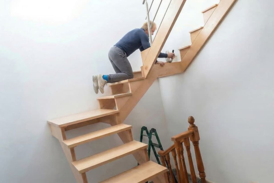 Carpintero profesional realizando el montaje de una escalera de madera en el domicilio de un cliente.